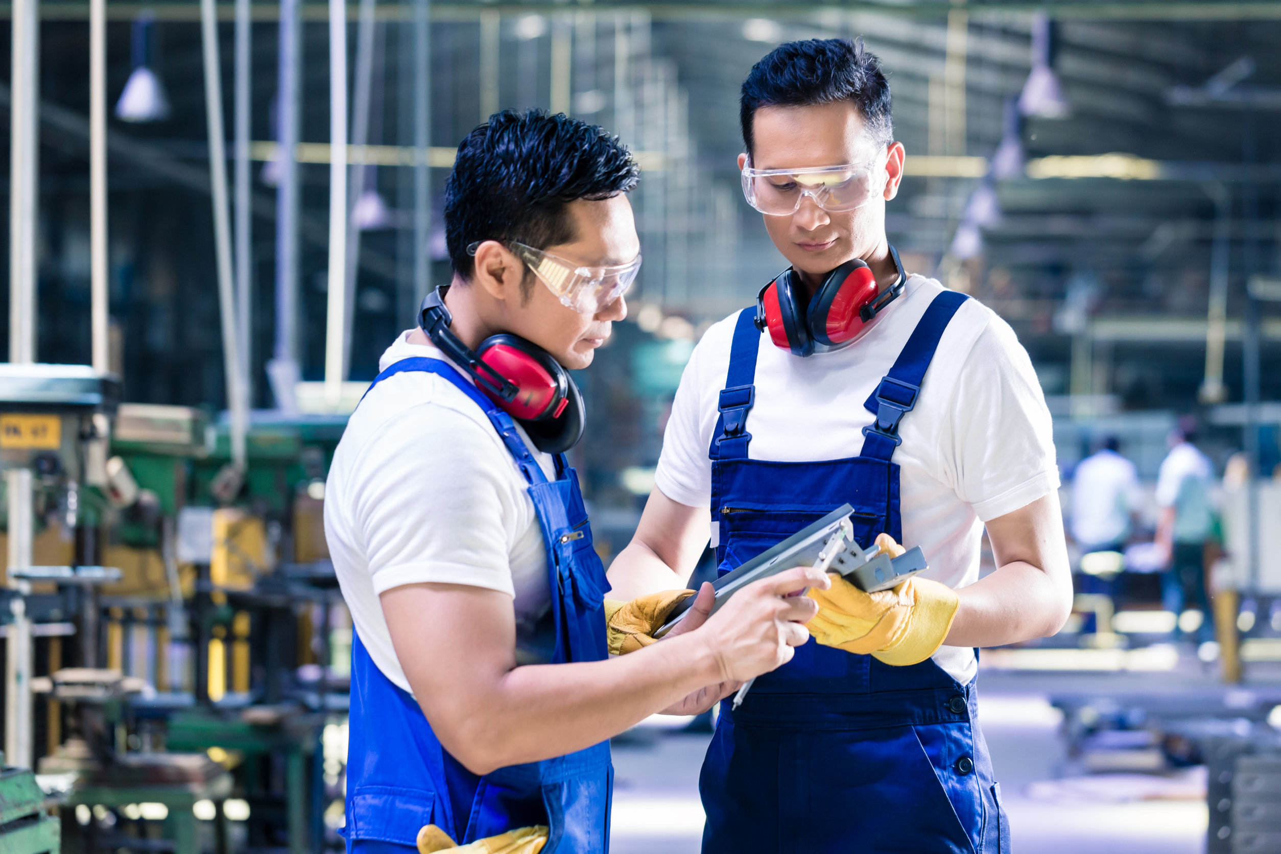 Asian worker checking work piece in production plant